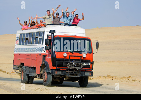 Eine Überland Abenteuer Urlaub LKW und seine Passagiere winken als es reist durch das Nationalreservat Paracas in Peru. Stockfoto