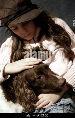 Mädchen von zehn Jahren suchen nachdenklich mit Hund auf dem Schoß sitzen Stockfoto