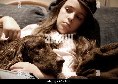 Mädchen von zehn Jahren suchen nachdenklich mit Hund auf dem Schoß sitzen Stockfoto