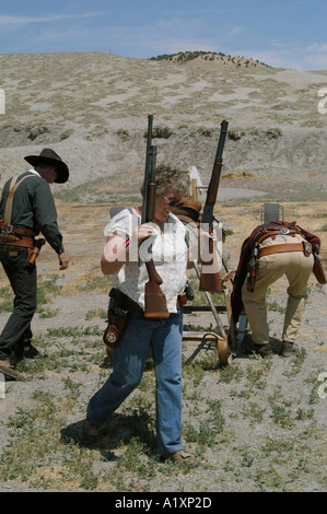 Über antike Feuerwaffen ältere Mitglieder einer Colorado Gun Club der Comanche Tal Vigilantes dress up und neu erlassen, die Szenen aus dem Wilden Westen für Ihre eigene Unterhaltung Hier eine ältere Frau, die zwei große Gewehre in der Luft hält Stockfoto