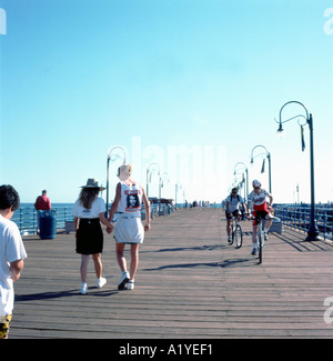Santa Monica Pier Frau Radfahren zum Pier auf der Straße von Sinbad's und Leute bummeln in 1990 Los Angeles, Kalifornien, USA KATHY DEWITT Stockfoto
