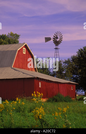 Nostalgie: Eine klassische Rote Scheune auf einem Bauernhof der Familie mit alten Mühle mit einem bunten Sonnenuntergang Dämmerung siedelt sich in, Missouri USA hervorgehoben Stockfoto