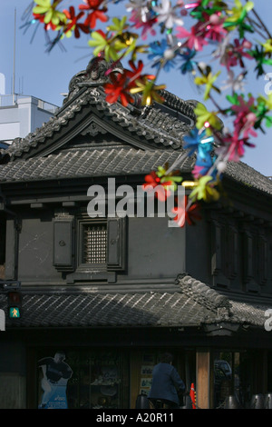 Künstlichen Plastikblumen vor einem alten 18. Jahrhundert geschwärzt Kurazukuri Kaufleute Lagerhäuser, Kawagoe, Japan Stockfoto