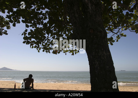 Brasilianischen Mann sitzt, trinken ein Bier neben der Brandung am Strand in Port Stadt Itajai, Brasilien. Stockfoto