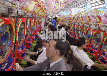 Japanische Spieler spielen die beliebten Pachinko Spielautomaten in Jumbo Pachinko Stube, Tokio, Japan. Stockfoto