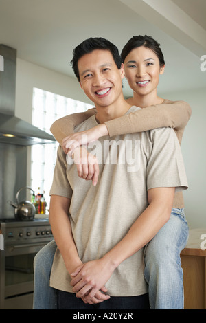 Frau sitzt auf der Arbeitsplatte, Arme um stehende Mann Stockfoto