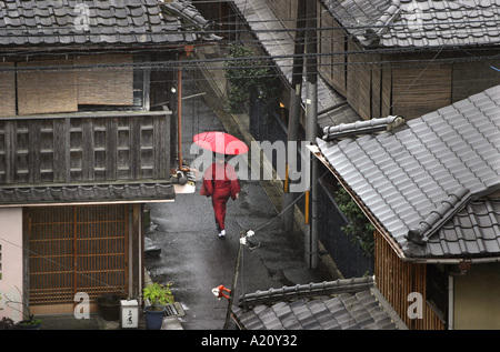 Frau trägt einen roten Kimono und tragen einen roten Regenschirm geht durch den Regen in den alten Straßen von Gion Bezirk von Kyoto, Japan Stockfoto