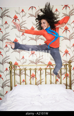 Teenager-Mädchen, ausgebreiteten Armen, treten, springen auf Bett Stockfoto