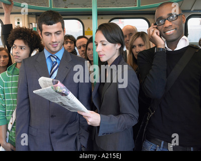 Pendler auf Zug stehen, Zeitung lesen, sprechen auf dem Handy Stockfoto