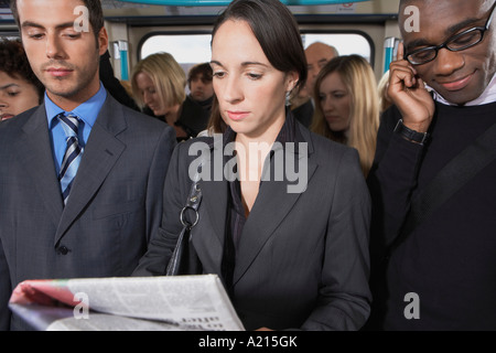 Pendler auf Zug stehen, Zeitung lesen, sprechen auf dem Handy Stockfoto