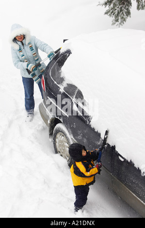 Mutter und Sohn Bürsten Schnee von Van Stockfoto