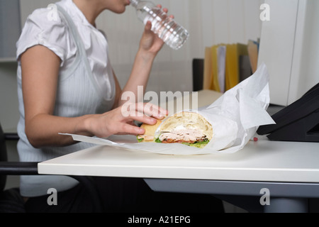 Geschäftsfrau Essen am Schreibtisch Stockfoto