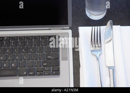 Laptop neben Gedeck Stockfoto