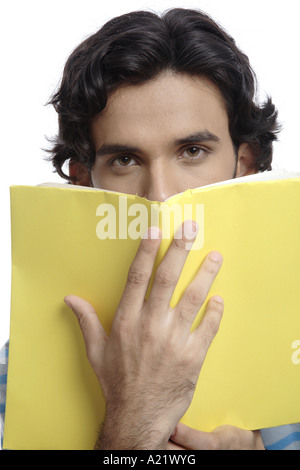 ANG200513 Teenager halten gelbes überdachte Buch vor sein Gesicht Herr 687T Stockfoto