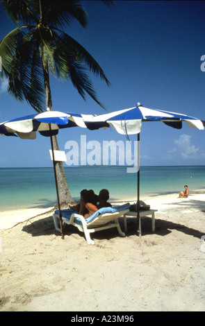 Einstellung der tropischen Strand mit Sonnenschirm und Liegestuhl vor einem türkisfarbenen Meer und blauer Himmel Stockfoto