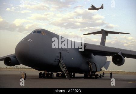 Ein USAF-C5-Galaxy bereitet zum Entladen der Fracht in Kuwait, während oben ein C130 Luft bekommt Stockfoto