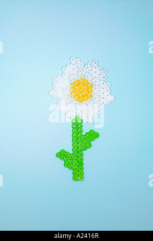 Kunststoff Blume aus Perler Perlen auf blauem Grund hergestellt. Stockfoto