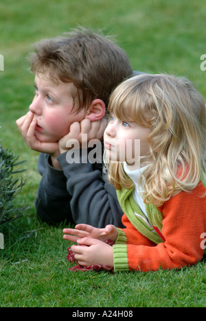 Jungen und Mädchen, die Verlegung auf dem Rasen, die gerade auf der Suche nachdenkliche Stimmung Stockfoto