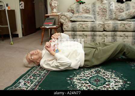 Senioren weiblich verwendet eine medizinische Alarm Alarmanlage für Notruf für Hilfe nach einem Sturz Stockfoto