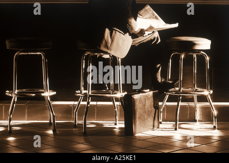 Geschäftsmann mit Zeitung und Aktenkoffer am Café-Schalter Stockfoto
