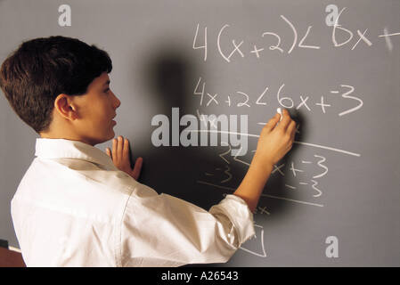 JUNGE, MATHEMATIK AN EINER TAFEL ARBEITET Stockfoto