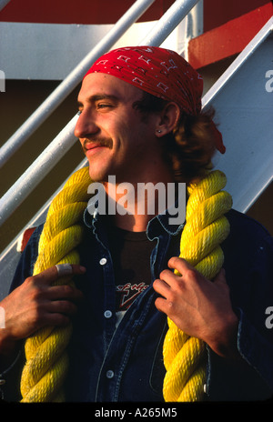 Profilbildnis einer amüsiert schnauzbärtige Deck Hand tragen in ein rotes Halstuch posiert mit einem dicken Abschnitt der hellen gelben Seil. Stockfoto