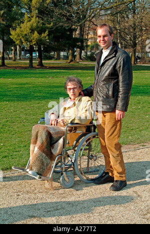 Herr Jüngling schieben einen Rollstuhl Rollstuhl mit einer alten Frau in einem Park im Frühling Stockfoto