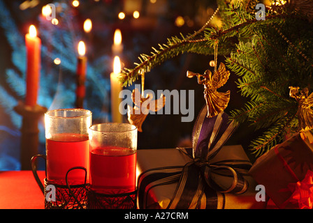 Heißes Getränk, Tee, Grog, Glühwein Wein mit brennenden Teelichtern und Geschenke unter einem Zweig eines Weihnachtsbaumes Stockfoto