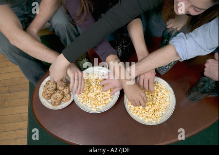 College-Mitbewohner sitzen auf der Couch Naschen auf Popcorn und cookies Stockfoto