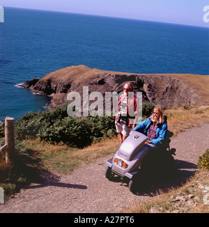 Ein paar navigieren in der Küstenstadt Fußweg auf einem Elektromobil im Sommer nördlich von Llangranog Ceredigion Wales UK KATHY DEWITT Stockfoto