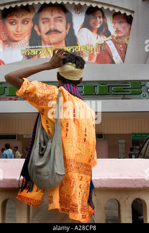 Indischer Sadhu-Priester in Safrankleidung mit Schultertasche und Blick auf Mangal Pandey Amir Khan Kinoplakat Indien Asien Stockfoto