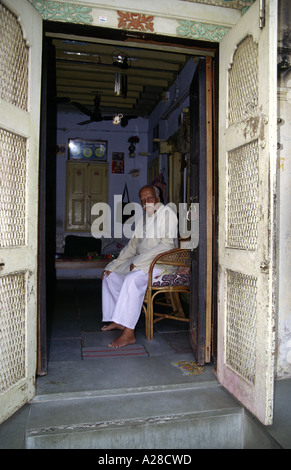 Älteren indischen Mann in traditioneller Tracht sitzt an der Tür seines Hauses, Ahmedabad, Gujarat Stockfoto