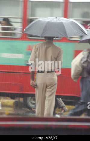 Polizist steht mit offenem Schirm im Regen, Siddhivinayak Tempel, Mumbai, Maharashtra, Indien Stockfoto
