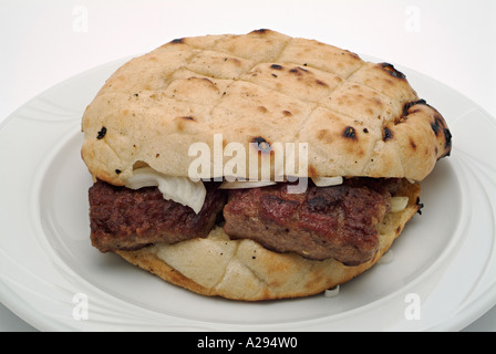 Ćevapčići, die traditionelle bosnische Gerichte aus 50 % gehackter Lamm und 50 % in ein Brot Farl mit frisch geschnittenen Zwiebel gehackter Rindfleisch serviert Stockfoto