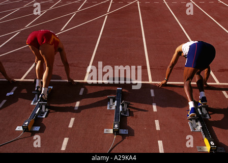 Ansicht von hinten zwei männliche Athleten in ihre Blockaden auf dem Weg zum Jahresbeginn eine Sprint-Rennen Stockfoto