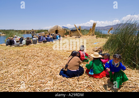 Einer einheimischen Familie in den Vordergrund und Touristengruppe mit Anleitung erklärt die Geschichte des Blattes Inseln des Titicacasees. Stockfoto