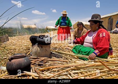 Eine niedrige Weitwinkelaufnahme einer lokalen Frau mit traditionellen Kochmethoden auf die Schilfinseln des Titicacasees. Stockfoto