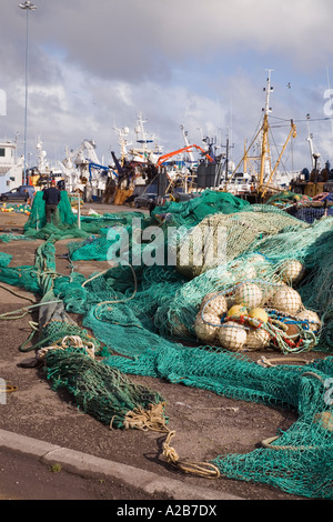 Fischernetze ausgebreitet auf Dock im Hafen mit pelagischen vertäuten Fischerbooten Castletownbere Co Cork Irland Stockfoto