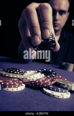 Junger Mann, der Chips in Topf in Poker-Spiel Stockfoto