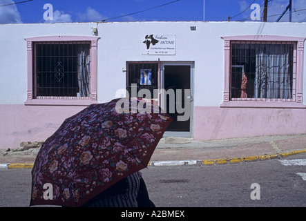 Frau mit Sonnenschirm und ein Schneider s Workshop in Marigot eine Stadt im französischen Teil der Insel Saint Martin genannt auch Sint Maarten Stockfoto