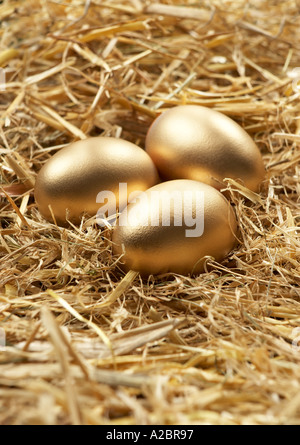 DREI GOLDENEN EIERN IM NEST AUS STROH Stockfoto