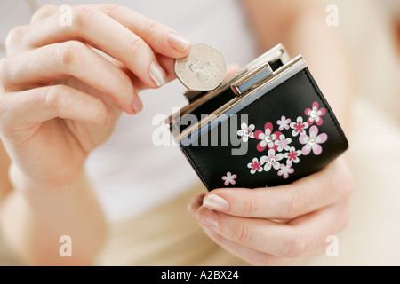 junge Frau, die Münzen im Geldbeutel setzen Stockfoto