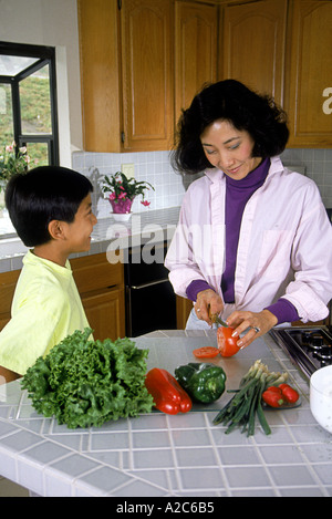Die chinesisch-amerikanische Mutter hört ihr Sohn die Arbeit in der Küche das Abendessen Salat ethnische Vielfalt unterschiedlicher Rasse multikulturellen Multi pov Zweisamkeit Stockfoto