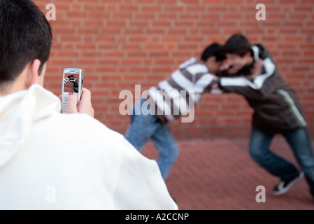 zwei Jungen kämpfen und gefilmt von einem anderen Stockfoto