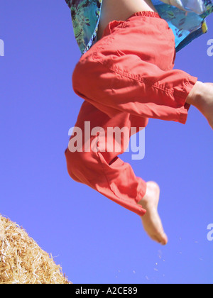 Ein vier Jahre alter Junge, springen von einem Heuhaufen in usa Stockfoto