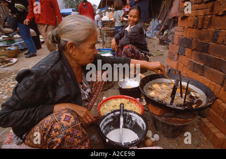 Alte Frau tief braten Snack Donuts am Morgen zu vermarkten, Luang Prabang, Laos Stockfoto