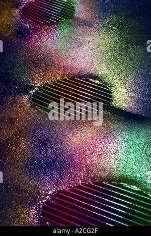 Sturm Kanalisation spiegelnde bunte Lichtern auf einer nassen Straße, regnerischen Nacht In Philadelphia Stockfoto