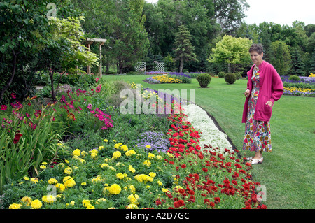 Eine Dame in leuchtend rosa Blüten in den Blumengärten der Kildonan Park in Winnipeg, Manitoba Kanada zu bewundern Stockfoto