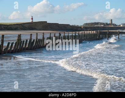 Blick vom Meer auf beschädigte Meer Verteidigung und Deckwerken, weit entfernten Leuchtturm und Kirche von happisburgh,, Norfolk, East Anglia, England, Großbritannien Stockfoto