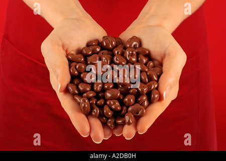 FRAU MIT HANDVOLL SCHOKOLADE BEDECKTE ROSINEN Stockfoto